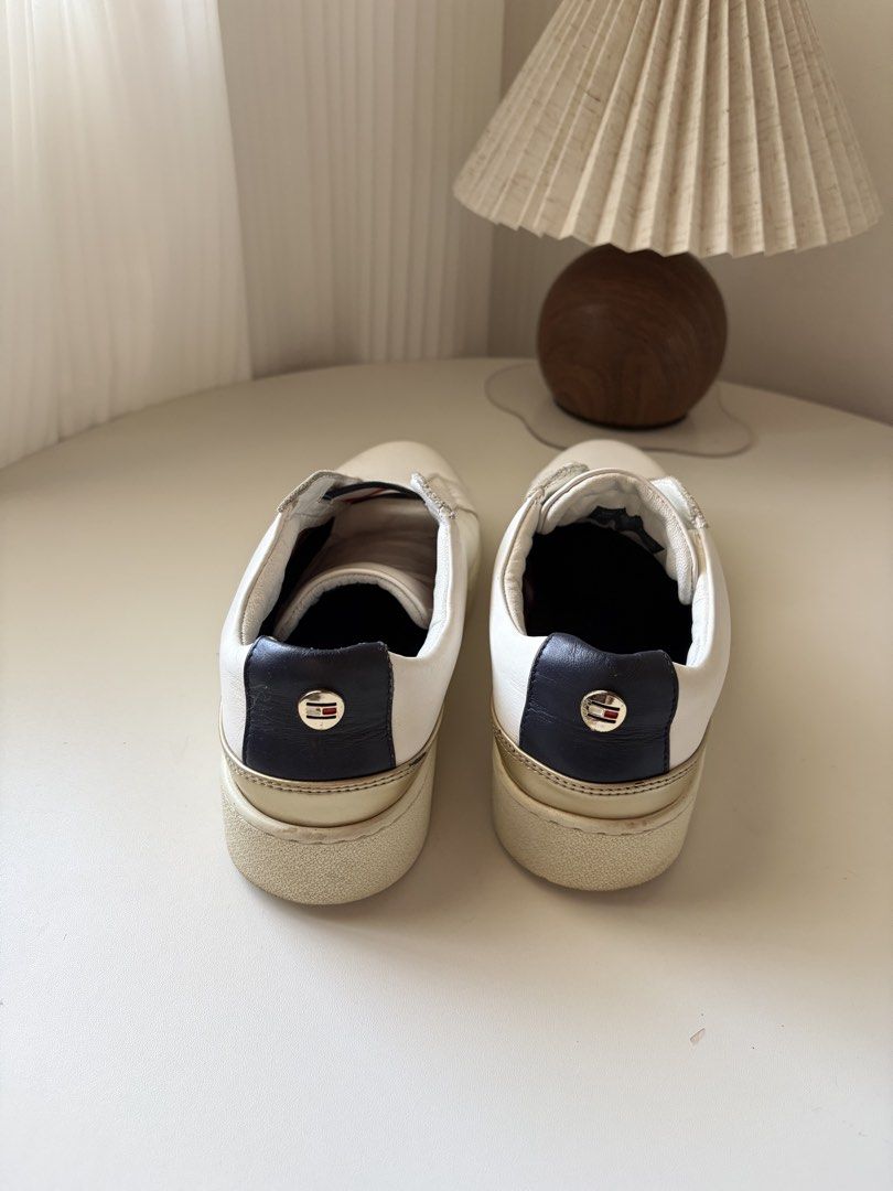 Tommy Hilfiger White Slip-On Sneakers (Category: Sneakers) located in Boac. Submitted by imjcueto (Listing ID 1453628372, Image 2). Description: - White Tommy Hilfiger slip-on sneakers - Features classic Tommy flag stripe detail - Gold accent on the heel - Tommy Hilfiger logo embossed on soles - Minor scuffs on soles and toe area - Still has lots of life left.