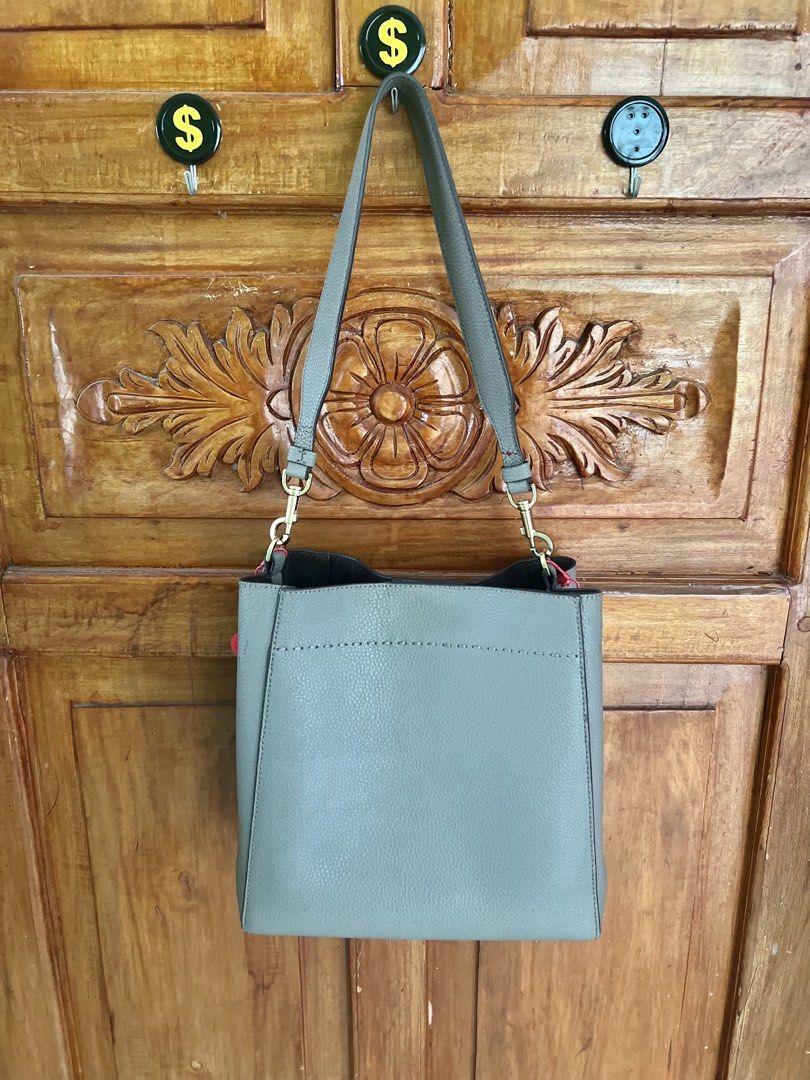 Tory Burch Grey Leather Bucket Tote Bag (Category: Luxury Bags & Wallets) located in San Fernando. Submitted by prettyfinds2021 (Listing ID 1453680516, Image 2). Description: - Brand: Tory Burch - Color: Grey - Material: Leather - Style: Bucket Bag - Features: Top handle, crossbody strap, interior zip pocket, snap closure - Extras: Cute red pom-pom charms - Ideal for: Everyday use.