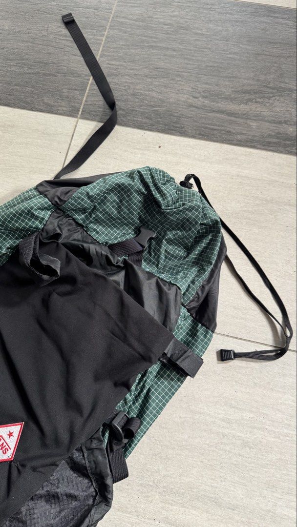 ULA CDT Backpack (Category: Hiking & Camping) located in Kuala Lumpur. Submitted by photophobia (Listing ID 1453789939, Image 2). Description: - Vans ULA CDT backpack - Green and black checkered pattern on top - Black front panel with Vans logo - Multiple external pockets and straps for organization - Secure drawstring closure at the top - Adjustable shoulder straps and hip belt for comfort - Ideal for hiking adventures or travel.