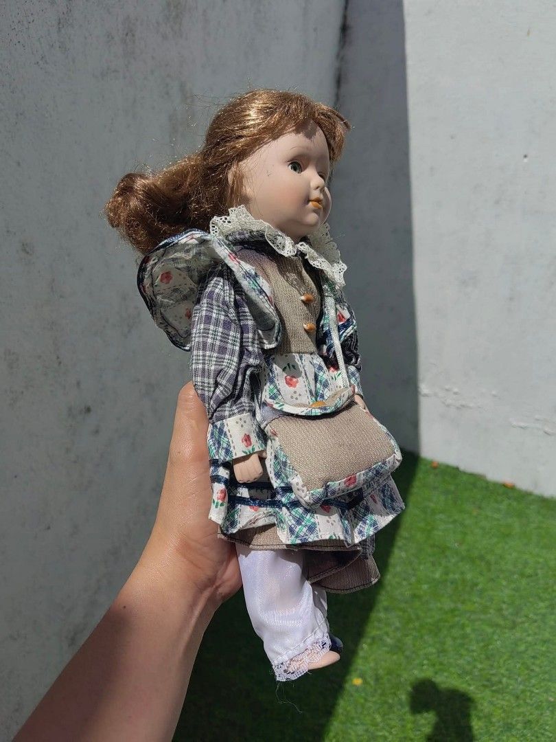 Vintage Porcelain Doll (Category: Vintage Collectibles) located in Cebu City. Submitted by dudes_villanueva (Listing ID 1453673522, Image 3). Description: Vintage Porcelain Doll 📌 featuring a molded bisque porcelain face, vibrant green glass inset eyes, and auburn hair. 📌 It is dressed in an ornate, country-style outfit consisting of a plaid patchwork fabric dress, an integrated brown vest section with decorative yellow buttons, a matching over