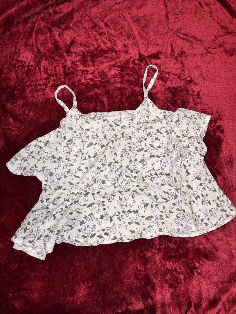 White Floral Strappy Ruffle Top (Category: Sleeveless) located in Batangas. Submitted by puccagirlypop (Listing ID 1453737614, Image 1). Description: Color: White with green and blue floral print Style: Double spaghetti straps with layered ruffle details and a relaxed flared hem Fabric: Lightweight woven fabric Size: Free size (Best fits Small to Medium) A dainty and cottagecore-inspired floral top! Perfect for beach trips, sunny day outs, or cas