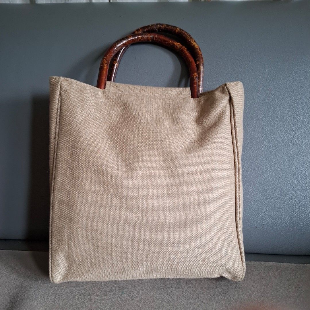 Agnes b. Canvas Tote Bag with Bamboo Handles (Category: Tote Bags) located in Don Carlos. Submitted by PphiXi_Finds (Listing ID 1453987497, Image 3). Description: - Agnes B Light beige canvas tote bag - Unique curved wooden handles - Interior slip pockets for organization - Ideal for everyday use or beach trips - Approx. 13" tall x 14" wide.