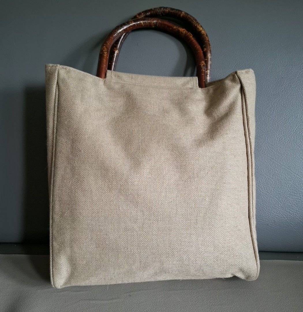 Agnes b. Canvas Tote Bag with Bamboo Handles (Category: Tote Bags) located in Don Carlos. Submitted by PphiXi_Finds (Listing ID 1453987497, Image 1). Description: - Agnes B Light beige canvas tote bag - Unique curved wooden handles - Interior slip pockets for organization - Ideal for everyday use or beach trips - Approx. 13" tall x 14" wide.