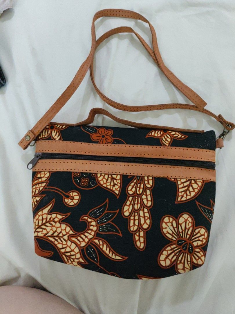 Batik Print Crossbody Bag with Leather Straps (Category: Cross-body Bags) located in Mandaue City. Submitted by regdeclutters (Listing ID 1453843888, Image 1). Description: From Indonesia cross body bag Black solid material. Cute batik print crossbody bag. Features a black background with orange and cream floral patterns. Has leather straps and zipper closures. The interior is lined with dark fabric. Great for carrying essentials. Measures about 