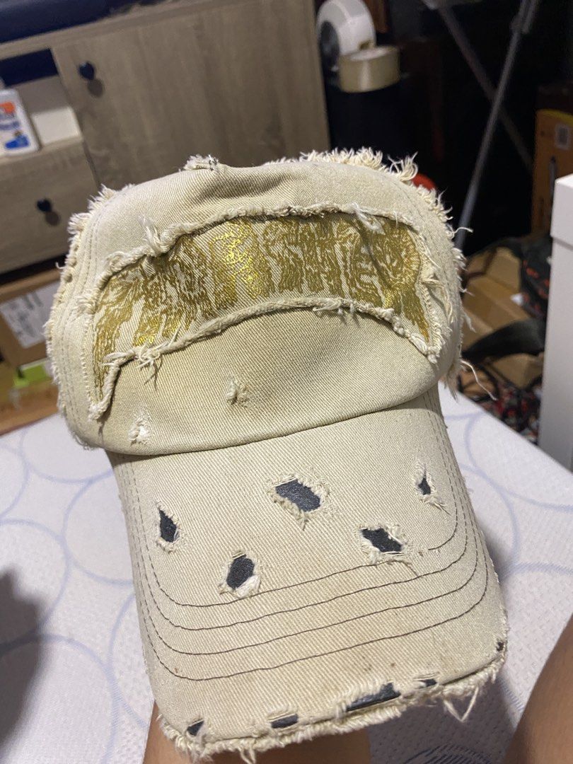 Distressed Baseball Cap with Gold Embroidery (Category: Caps & Hats) located in Manila. Submitted by cdb_22 (Listing ID 1453995924, Image 1). Description: - Tan distressed baseball cap - Features gold embroidery on the front - Intentionally ripped and frayed for an edgy look - Adjustable strap at the back for a custom fit - Ideal for a casual, street-style vibe.