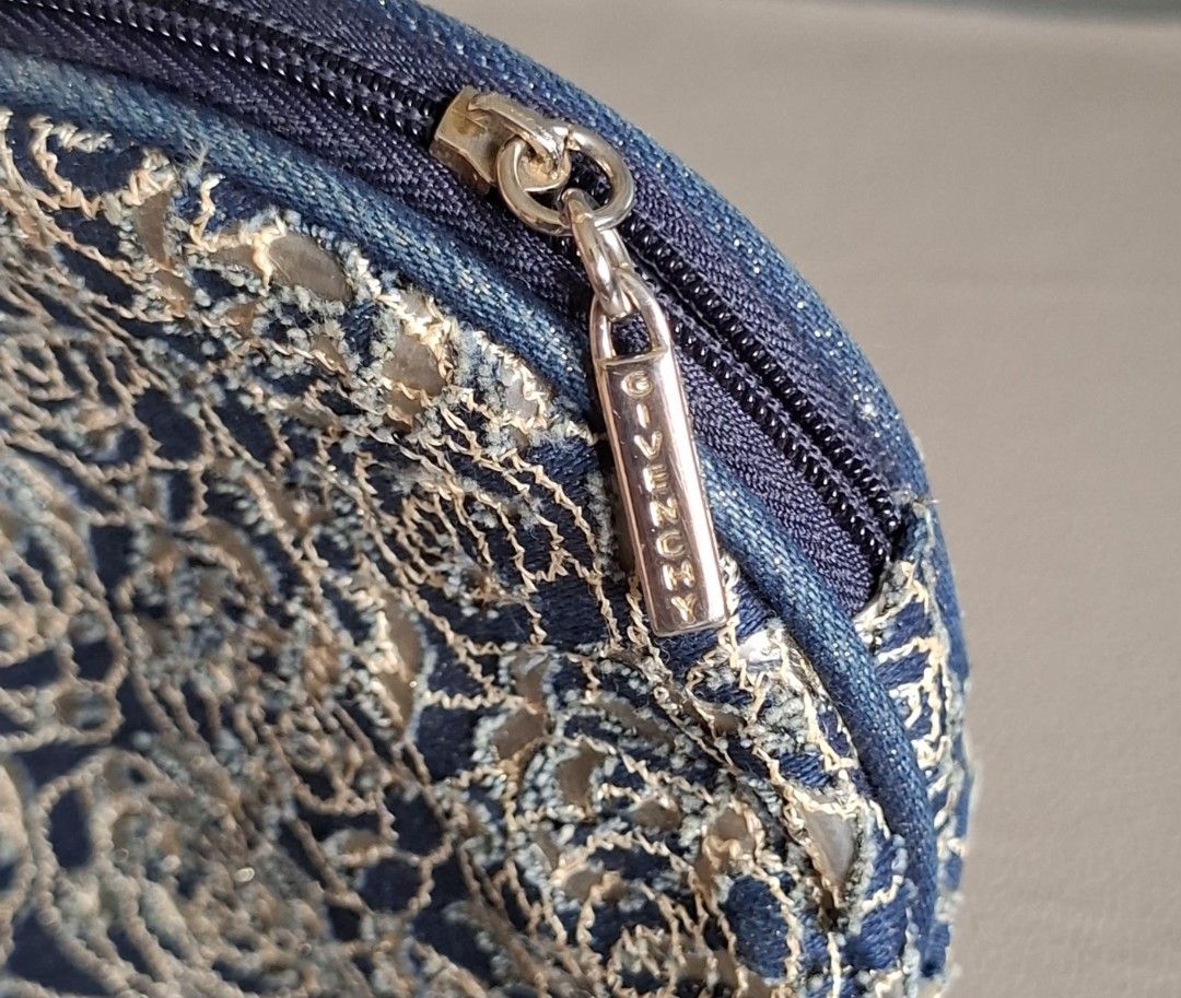 Givenchy Cosmetic Bag Blue Floral Lace (Category: Luxury Bags & Wallets) located in Don Carlos. Submitted by PphiXi_Finds (Listing ID 1453986417, Image 3). Description: - Cute Givenchy makeup pouch - Blue denim base with floral lace overlay - Zipper closure with branded pull tab - Lined interior - Ideal for organizing makeup and essentials - Approximately 7 inches wide.