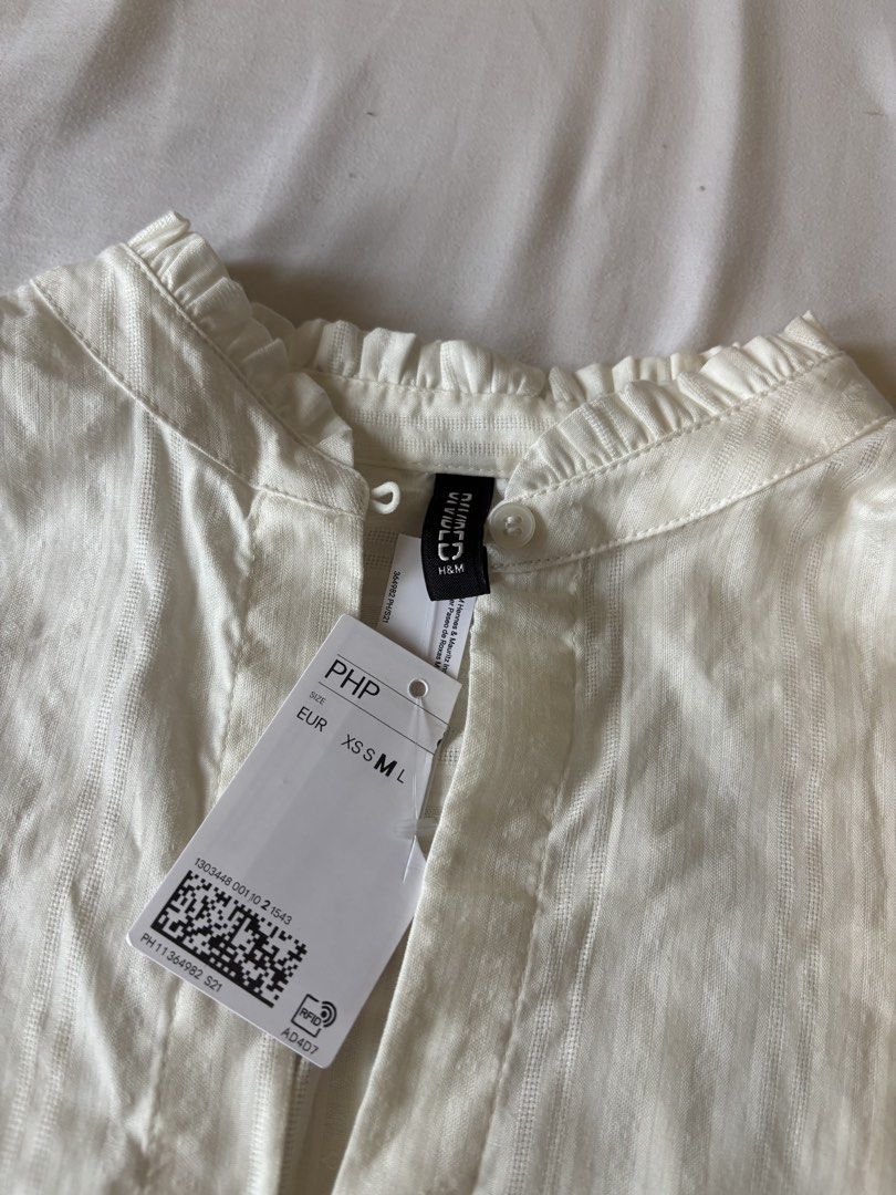 H&M Divided White Long Sleeve Blouse Top (Category: Blouses) located in Quezon City. Submitted by naomimen (Listing ID 1453915424, Image 3). Description: - White long sleeve blouse from H&M Divided - Elegant high neckline with a delicate keyhole detail - Brand new with tags - Subtle vertical stripe texture adds a touch of sophistication - Convenient button closure at the back of the neck - Comfortable long sleeves with elasticated cuffs - Versati