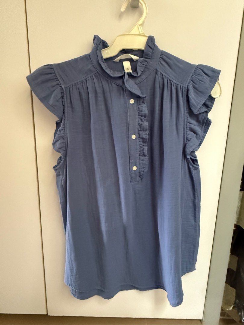 H&M Ruffle Neck Sleeveless Blouse (Blue/Grey) (Category: Blouses) located in Quezon City. Submitted by 0913cartz (Listing ID 1453952166, Image 1). Description: - Cute H&M sleeveless blouse - Features a ruffled neckline - Button details down the front - Adorable flutter sleeves - Versatile for casual or dressy occasions - Available in blue and grey.