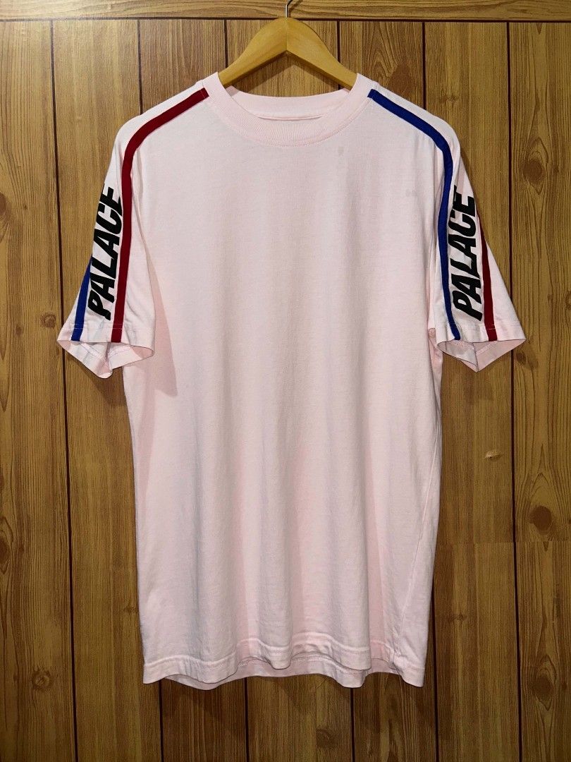 Pink Palace Sideline T-shirt (Category: Formal Shirts) located in Manila. Submitted by zerowastethriftco. (Listing ID 1453838735, Image 1). Description: The Palace Sideline T-Shirt is a highly sought-after streetwear piece from the brand's Fall/Winter 2019 (FW19) collection.Design & FeaturesColorway: A soft, pastel light pink base.Sleeve Details: Vibrant red and royal blue racing-style stripes run down the shoulders and arms.Branding: A bold, ita