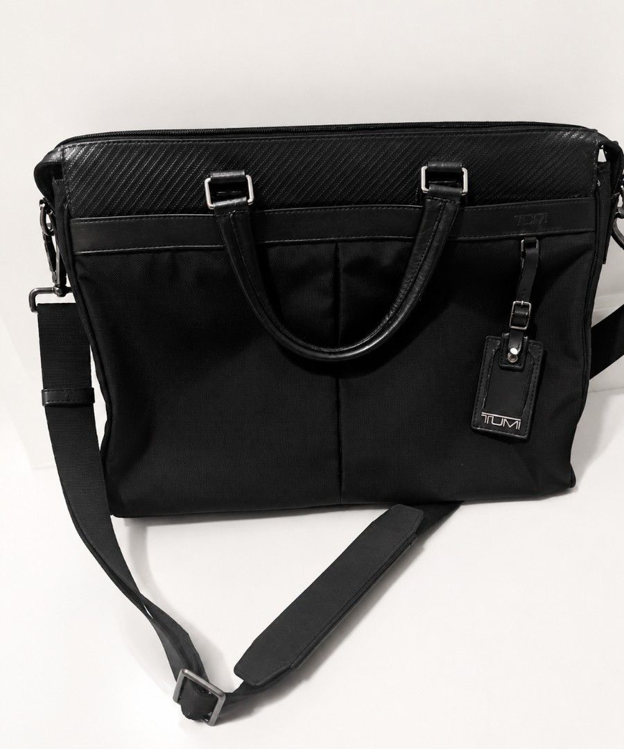 Tumi Black Briefcase Laptop bag with Shoulder Strap (Category: Briefcases) located in Manila. Submitted by seanapaul (Listing ID 1438426103, Image 1). Description: - Black Tumi briefcase - Includes a detachable shoulder strap with padded rest - Multiple interior compartments - Secure zip closure - Comfortable leather handle - Authentic Tumi tag - Striped interior lining - Compartment to open and fix onto carry on luggage .