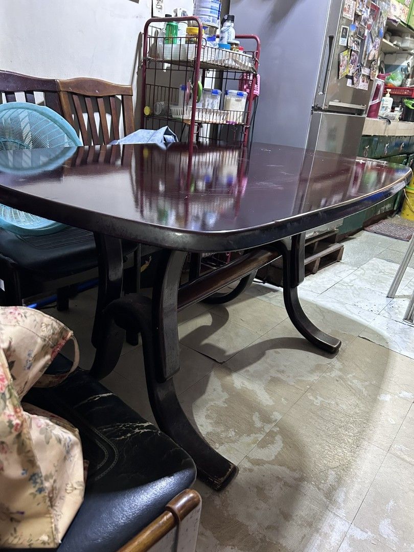 Wooden Dining Table with 6 Chairs (Category: Tables & Sets) located in Caloocan City. Submitted by happyjams (Listing ID 1453948401, Image 1). Description: - Dark wood finish curved rectangular dining table - Includes 6 wooden chairs with black faux leather seats - Table surface has some scratches and signs of wear - Chair seats show some wear - Ideal for family mealtimes.