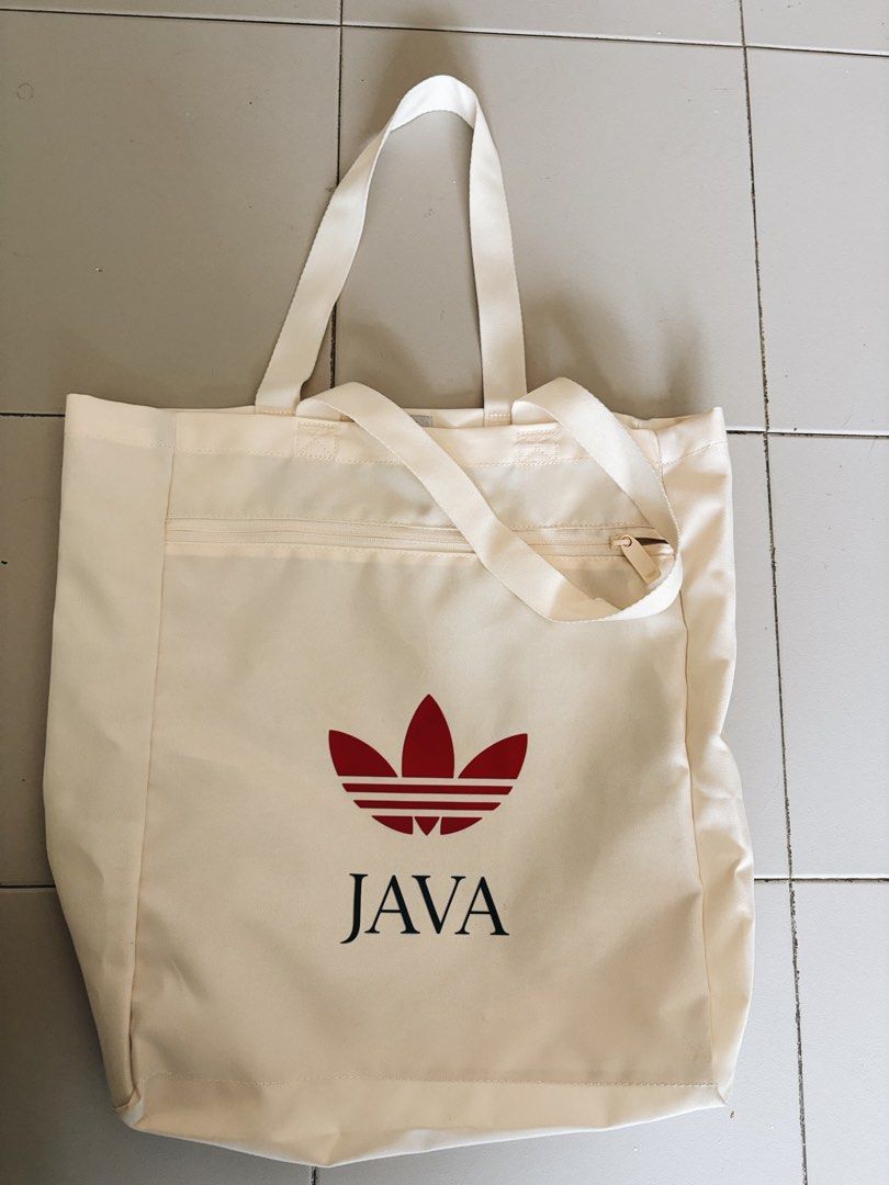 Adidas Java Tote Bag (Category: Sling Bags) located in Singapore. Submitted by BakerTed (Listing ID 1454029593, Image 1). Description: - Cream colored tote bag - Iconic red Adidas trefoil logo - 'JAVA' text detail - Zippered front pocket for secure storage - Internal smaller pocket for organization - Comfortable handles for easy carrying - Perfect for everyday use.