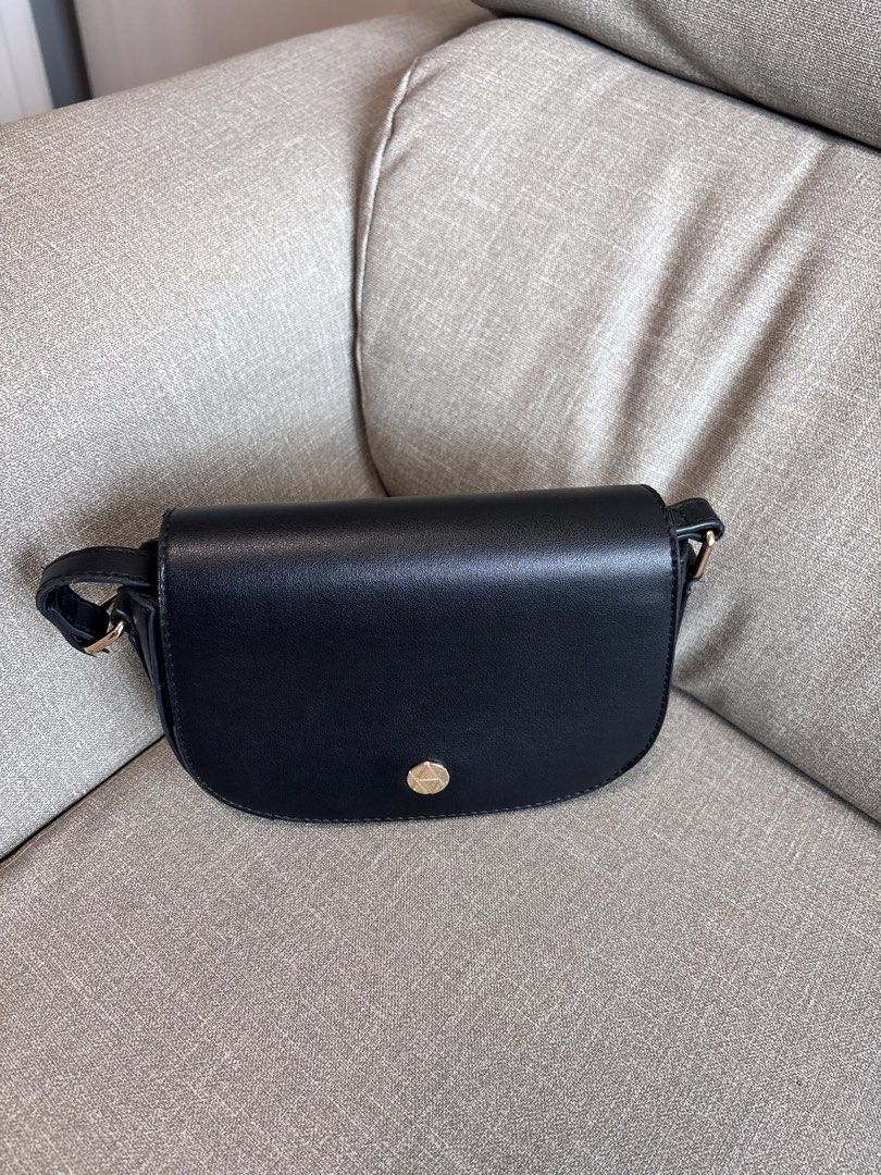 Black Saddle Crossbody Bag with Gold Clasp (Category: Cross-body Bags) located in Paranaque City. Submitted by jujudeclutterss (Listing ID 1454023978, Image 1). Description: - Bought from Malaysia - Cute black saddle bag - Secure gold clasp closure - Adjustable strap for comfort - Spacious main compartment - Fits your daily essentials (phone, wallet, keys) - Clean interior - Minor signs of wear on the exterior, adding character - Ideal for everyd