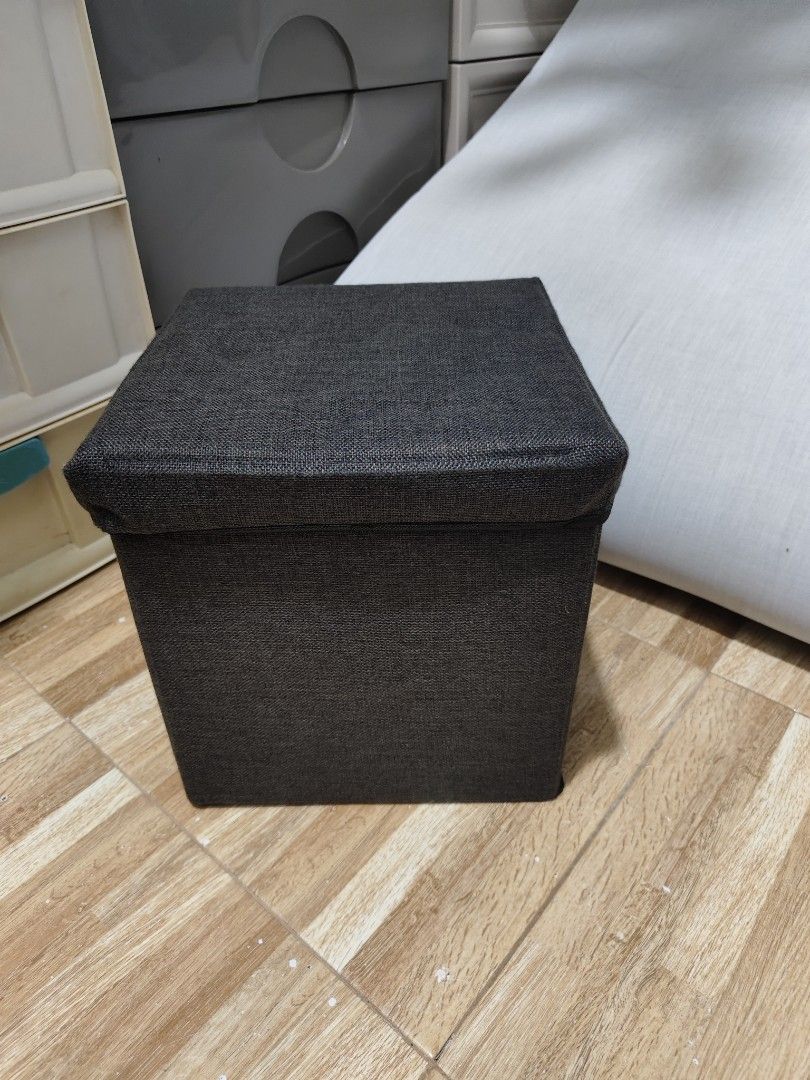 Dark Grey Fabric Storage Ottoman Footrest Stool (Category: Chairs) located in Makati City. Submitted by abegailbrezuela (Listing ID 1454124995, Image 1). Description: - Dark grey fabric storage ottoman - Versatile: use as a footrest or extra seating - Lid lifts for convenient internal storage - Folds flat for easy storage when not in use - Perfect for organizing clutter - Approximate dimensions: 15" x 15" x 15".