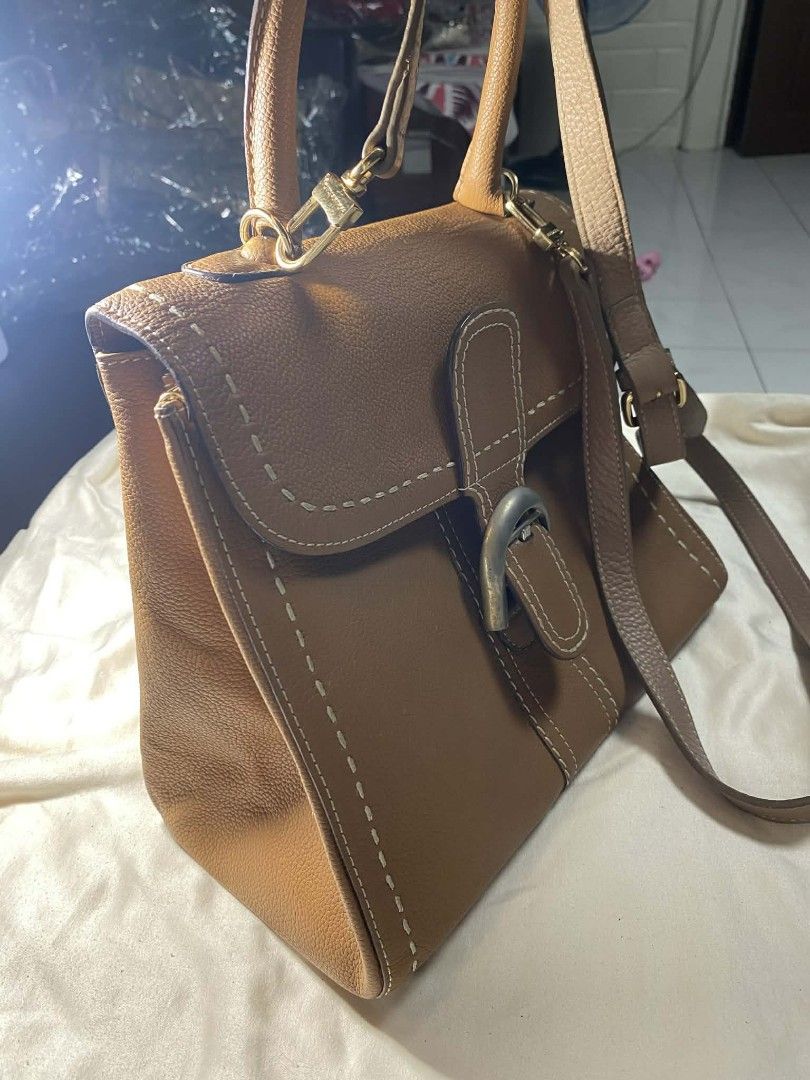 DELVAUX Brown Leather Handbag Shoulder Bag (Category: Luxury Bags & Wallets) located in Manila. Submitted by vasttree.6bc15f (Listing ID 1454111414, Image 2). Description: - Genuine brown leather with eye-catching contrast stitching. - Versatile carrying options: top handle and detachable shoulder strap. - Secure front flap with a classic buckle closure. - Organized interior with one zippered pocket and one slip pocket. - Protective metal feet on