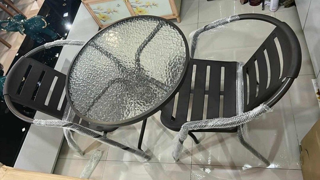 Glass Top Bistro Set with 2 Chairs (Category: Tables & Sets) located in Mandaluyong City. Submitted by carmy.94 (Listing ID 1454042912, Image 1). Description: - Round glass top table with textured pattern - Includes two modern metal chairs with slatted design - Perfect for small spaces like balconies or patios - Great for enjoying coffee or drinks outdoors - Easy to clean and maintain.