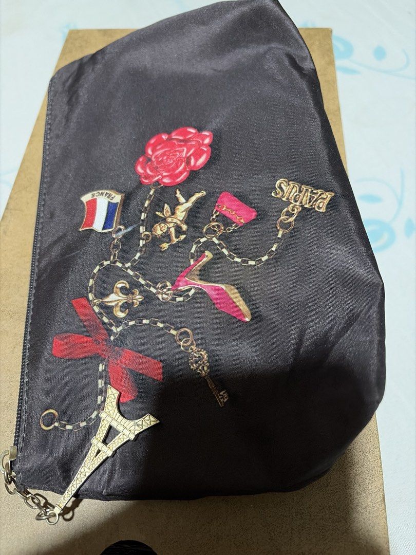 Lancome Paris Cosmetic Bag with Eiffel Tower Charm (Category: Makeup) located in Las Pinas. Submitted by ces0427 (Listing ID 1454187005, Image 2). Description: - Cute makeup pouch from Lancome Paris. - Features a dark brown exterior. - Adorned with fun Paris-themed charms: Eiffel Tower, rose, and high heel. - Secure zipper closure. - Interior displays the Lancome Paris label. - Ideal for travel or everyday use to keep essentials organized..