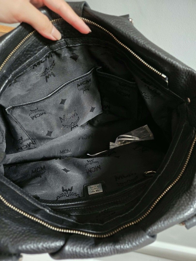MCM Black Leather Tote Bag (Category: Luxury Bags & Wallets) located in Bangued. Submitted by shopaholic.girliee. (Listing ID 1454050352, Image 3). Description: - Genuine black leather MCM tote bag - Spacious interior with signature MCM logo lining - Secure zipper closure - Durable, sturdy handles for everyday carrying - Shows slight signs of wear on the rubber lining of the handles - Sling strap has a few cracks (see last image).