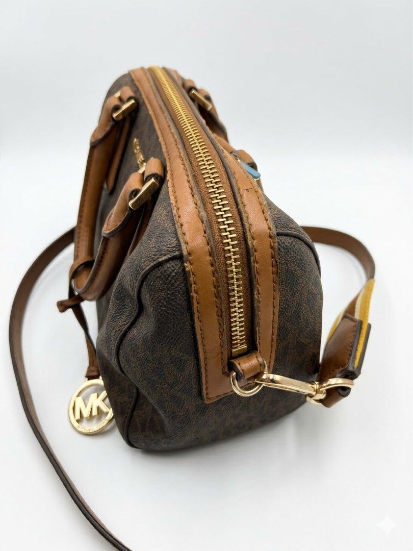 Michael Kors Monogrammed Barrel Bag with Strap (Category: Luxury Bags & Wallets) located in Munoz. Submitted by Liiz27 (Listing ID 1454065553, Image 2). Description: - Authentic Michael Kors barrel bag - Signature MK monogram print - Comes with a brown and yellow striped crossbody strap - Gold hardware details - Interior zip pocket - Minor signs of wear on leather trim and interior.