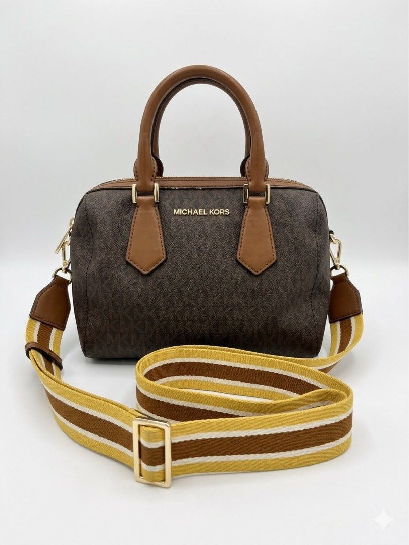 Michael Kors Monogrammed Barrel Bag with Strap (Category: Luxury Bags & Wallets) located in Munoz. Submitted by Liiz27 (Listing ID 1454065553, Image 1). Description: - Authentic Michael Kors barrel bag - Signature MK monogram print - Comes with a brown and yellow striped crossbody strap - Gold hardware details - Interior zip pocket - Minor signs of wear on leather trim and interior.