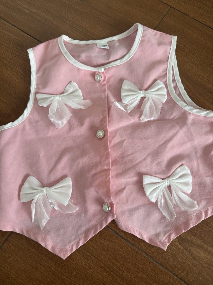 Pink Coquette Vest with Pearl Buttons (Category: Babies & Kids Fashion) located in Bulacan. Submitted by emjay_17 (Listing ID 1454052155, Image 1). Description: - Cute pink baby vest - White trim around edges - Four white bows on the front - Three pearl-like buttons down the middle - Toddler size - Ideal for dressing up or special occasions - Plain pink back.