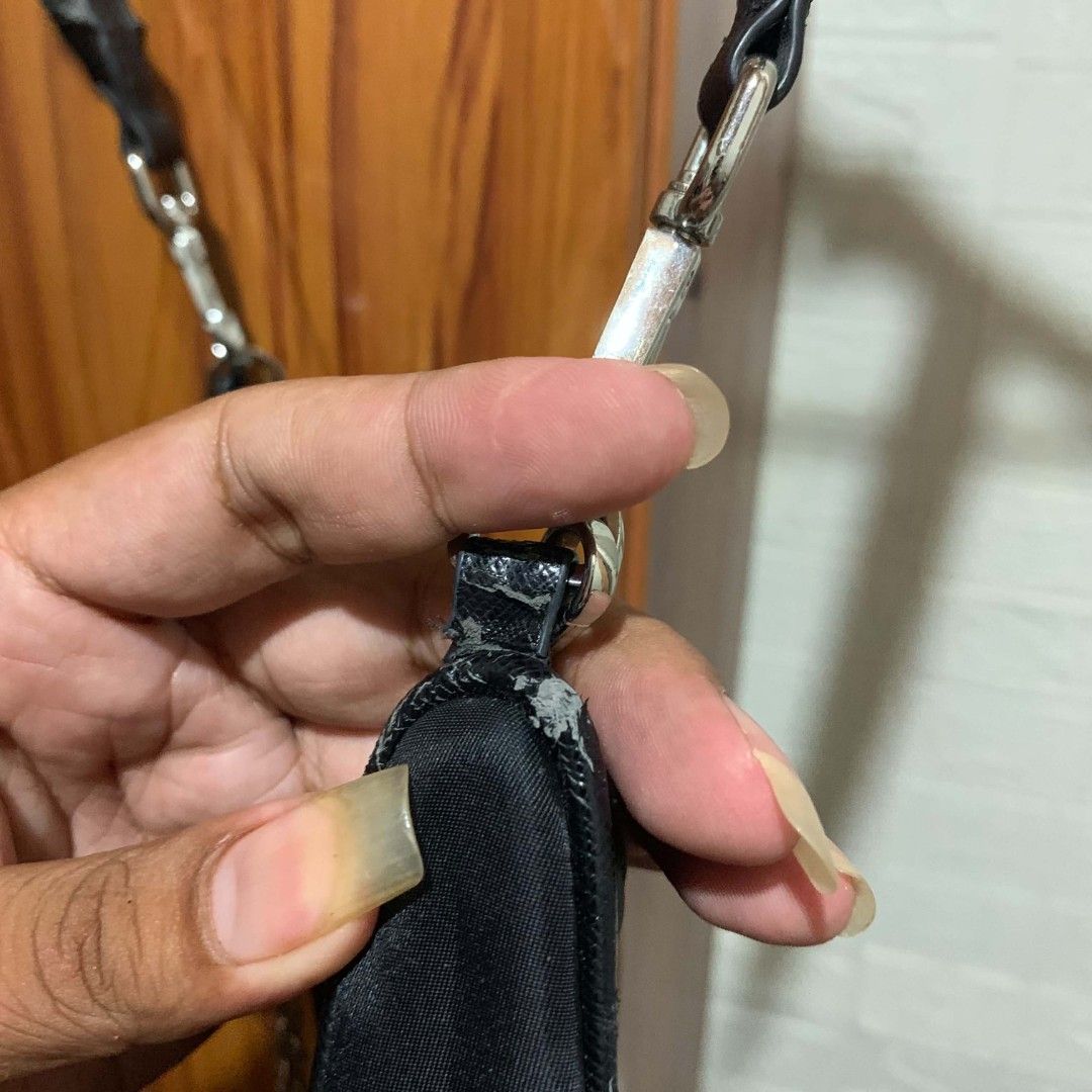 Prada Re-Edition 2005 Nylon Shoulder Bag Black (Category: Luxury Bags & Wallets) located in Carmen. Submitted by ar_thrift00 (Listing ID 1454129475, Image 2). Description: - Prada Re-Edition 2005 shoulder bag - Chic black nylon material - Elegant silver chain detail - Iconic Prada logo prominently displayed on the front - 'PRADA' branding on the shoulder strap - Shows some minor signs of wear on the strap attachment point.