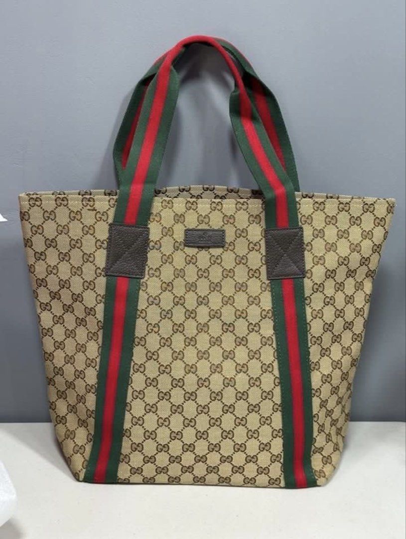 Preloved bag (Category: Luxury Bags & Wallets) located in Los Banos. Submitted by ditasbautista2329 (Listing ID 1454183802, Image 1). Description: Gucci tote bag featuring the iconic GG canvas pattern. It has the signature green and red stripe detailing on the straps. The interior is lined with a dark fabric and includes a small pocket. The bag has a leather tag with the Gucci logo and a serial number inside..
