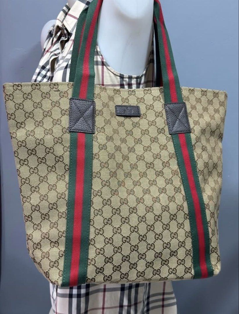 Preloved bag (Category: Luxury Bags & Wallets) located in Los Banos. Submitted by ditasbautista2329 (Listing ID 1454183802, Image 2). Description: Gucci tote bag featuring the iconic GG canvas pattern. It has the signature green and red stripe detailing on the straps. The interior is lined with a dark fabric and includes a small pocket. The bag has a leather tag with the Gucci logo and a serial number inside..