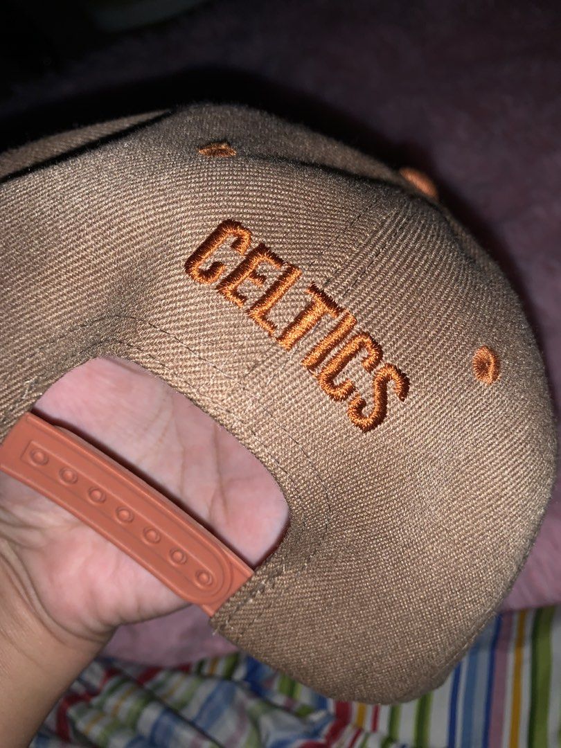 Real Fire Boston Celtics Snapback Cap (Category: Caps & Hats) located in Binan City. Submitted by kariray_shop (Listing ID 1454066140, Image 2). Description: - Brown snapback cap with official Boston Celtics logo - 'Celtics' embroidered on the back - Real Fire brand, original design - Adjustable strap for a comfortable fit - Perfect for any Boston Celtics fan.