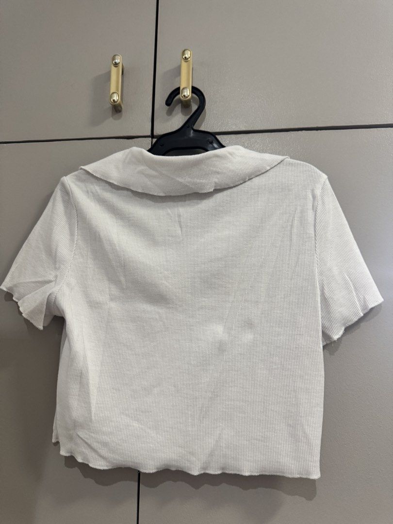 SHEIN White Ribbed Collared Button-Up Crop Top Size M (Category: Blouses) located in Quezon City. Submitted by jaebaeee (Listing ID 1454141311, Image 3). Description: - White ribbed crop top from SHEIN - Collared neckline - Button-up front - Short sleeves with lettuce hem - Versatile for casual or dressed-up looks.