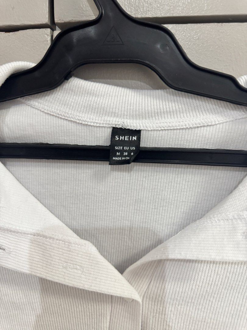 SHEIN White Ribbed Collared Button-Up Crop Top Size M (Category: Blouses) located in Quezon City. Submitted by jaebaeee (Listing ID 1454141311, Image 2). Description: - White ribbed crop top from SHEIN - Collared neckline - Button-up front - Short sleeves with lettuce hem - Versatile for casual or dressed-up looks.