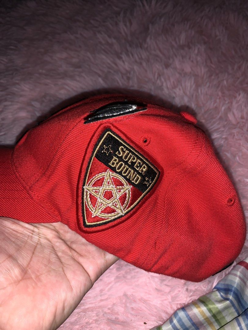 Super Massive Bound Red Cap with 'M' Logo and Devil Wings (Category: Caps & Hats) located in Binan City. Submitted by kariray_shop (Listing ID 1454057259, Image 2). Description: - Red cap from Super Massive Bound - Features embroidered 'M' logo with devil horns and wings - 'Super Bound' patch with pentagram on the side - 'SMB' logo on the back - Tag indicates size XS - Ideal for streetwear or alternative fashion enthusiasts.