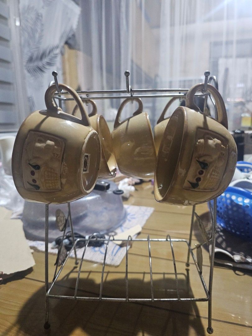 Vintage Ceramic Mugs with Holder (Category: Coffee & Tea Tableware) located in General Trias. Submitted by kittykate__ (Listing ID 1454129483, Image 2). Description: - Set of 5 ceramic mugs - Features a unique raised teapot design on each mug - Light brown color - Comes with a convenient metal rack for storage - Ideal for enjoying coffee or tea - Boasts a charming vintage aesthetic.