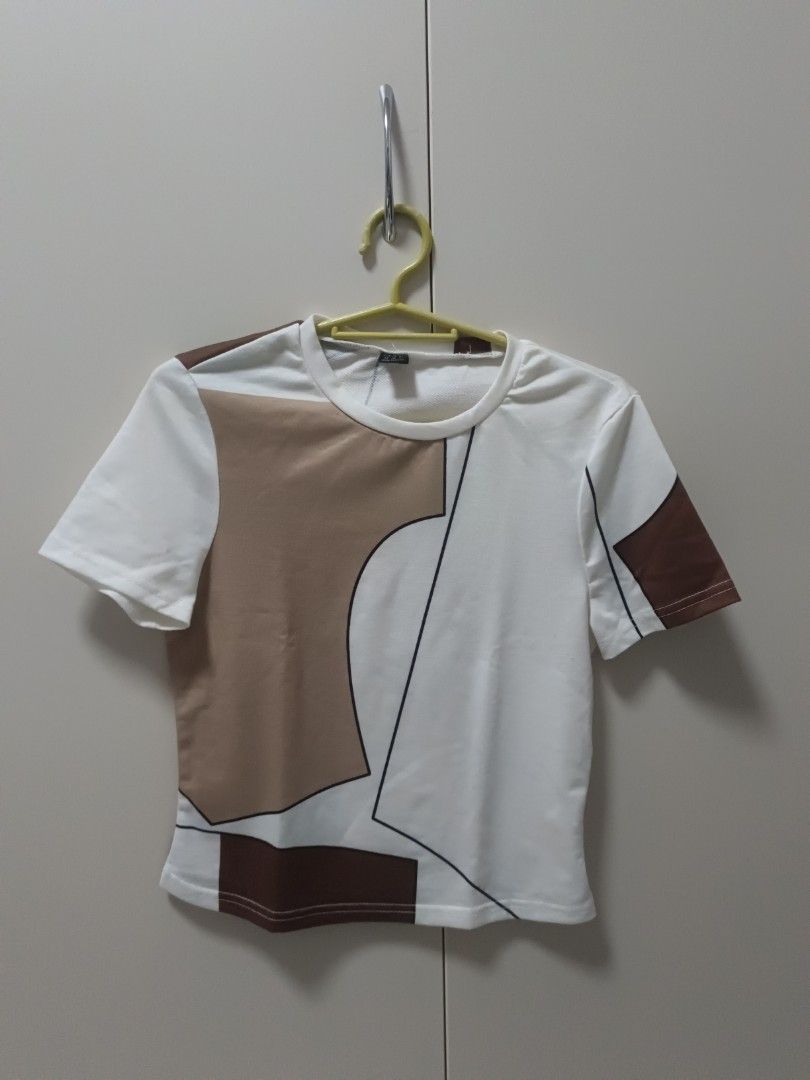 White Top with Abstract Brown and Black Print (Category: Others Tops) located in Lucena. Submitted by amara211629 (Listing ID 1454086672, Image 1). Description: - Unique abstract geometric print in brown and black on white. - Short-sleeved design. - Comfortable for everyday wear. - Versatile: easily pairs with jeans or shorts. - M on tag but best fit to small.