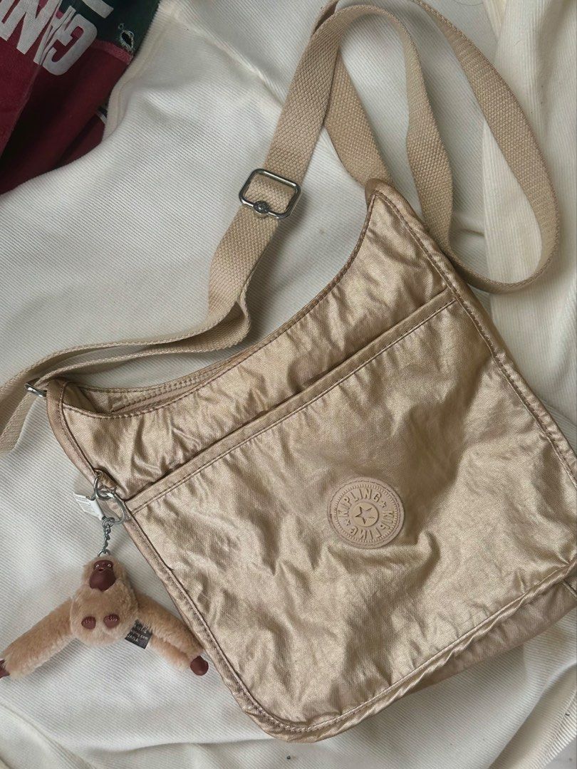 Kipling Metallic Gold Crossbody Bag with Monkey Charm (Category: Cross-body Bags) located in Manila. Submitted by bagified (Listing ID 1454209556, Image 1). Description: - Lightweight Kipling crossbody bag - Beautiful metallic gold color - Iconic Kipling monkey charm included - Features a front pocket - Interior zip pocket for secure storage - Adjustable strap for customized comfort - Ideal for everyday use.