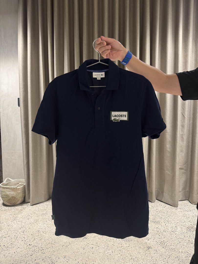 Lacoste Navy Blue Polo Shirt with Patch (Category: Tshirts & Polo Shirts ) located in Manila. Submitted by rb.declutters (Listing ID 1454338696, Image 1). Description: - Classic navy blue Lacoste polo shirt - Features iconic crocodile logo patch on chest - Short sleeves - Button-up collar - Versatile for casual or smart-casual wear - Pairs well with jeans or shorts.