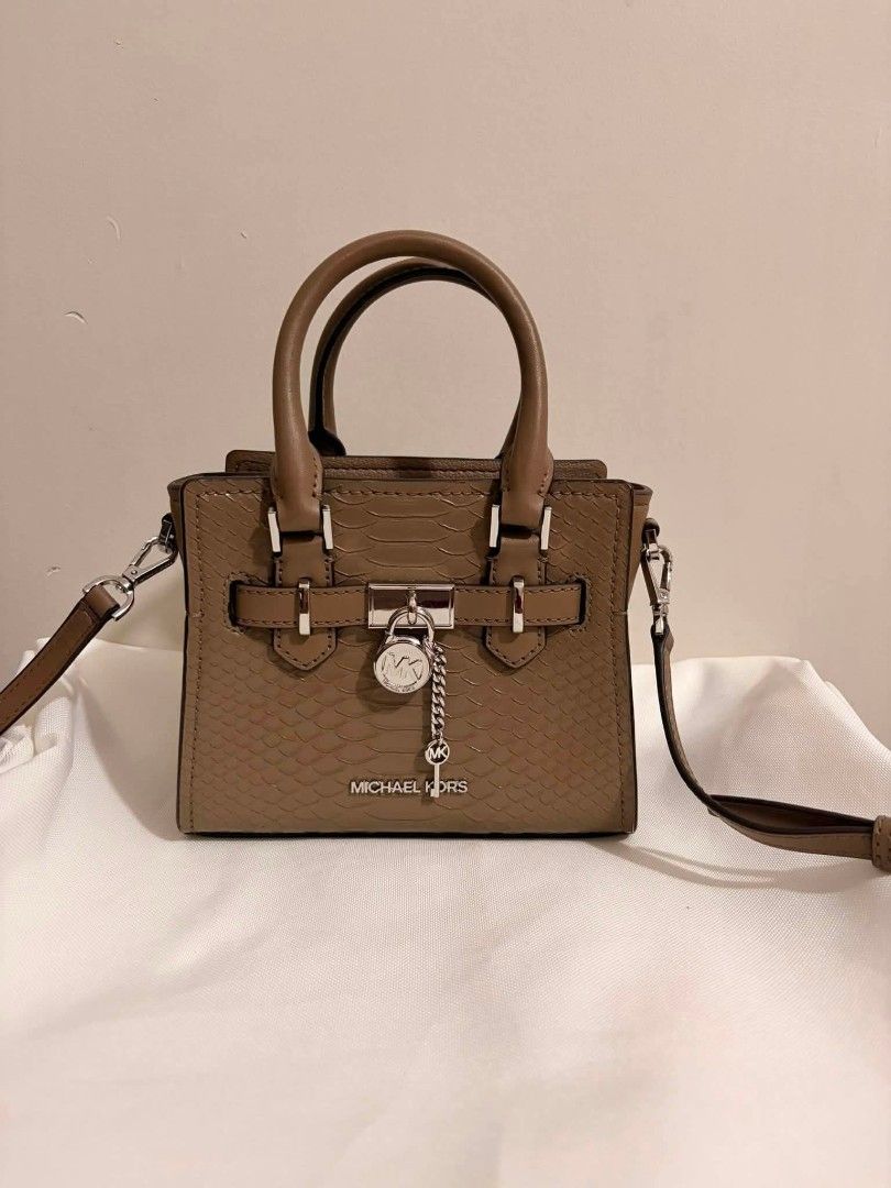 Michael Kors Snake Embossed Leather Satchel Handbag (Category: Luxury Bags & Wallets) located in San Pedro. Submitted by welloved.325 (Listing ID 1454318662, Image 1). Description: - Authentic Michael Kors handbag - Elegant taupe color with snake-embossed texture - Versatile: top handle and detachable shoulder strap - Secure lock closure with signature MK charm and key detail - Compact and stylish, ideal for daily use.