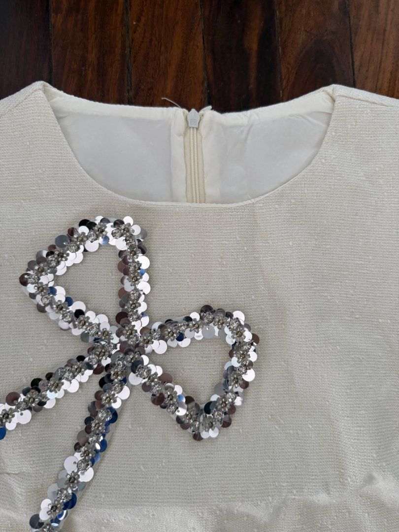 White sequin bow crop top and skirt set (Category: Sets or Coordinates) located in Pasig City. Submitted by atbp__ (Listing ID 1454303229, Image 3). Description: - Adorable white two-piece set - Sleeveless crop top with sparkly sequin bow detail - Matching high-waisted skirt - Zipper closure on the top - Ideal for parties and events - Sold as a set.
