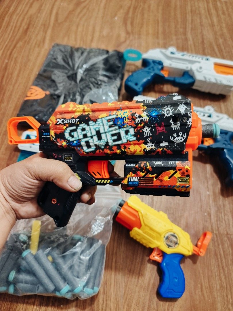 X-Shot Toy Guns Bundle with Darts and Bag (Category: Action & Battle Toys) located in Baguio. Submitted by jguerre2 (Listing ID 1454333732, Image 3). Description: - X-Shot Toy Gun Bundle - Includes 4 blasters with different designs - One blaster features a 'Game Over' theme - Three blasters are white and blue - Great for kids who love action play.