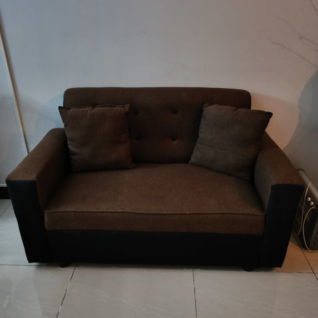 2-Seater Brown Fabric Sofa with Cushions (Category: Sofas) located in Manila. Submitted by brycee10 (Listing ID 1454497072, Image 1). Description: - Comfortable 2-seater sofa - Upholstered in brown fabric with black accents - Includes two matching throw pillows - Compact size, ideal for smaller living spaces - Great for lounging and relaxing .