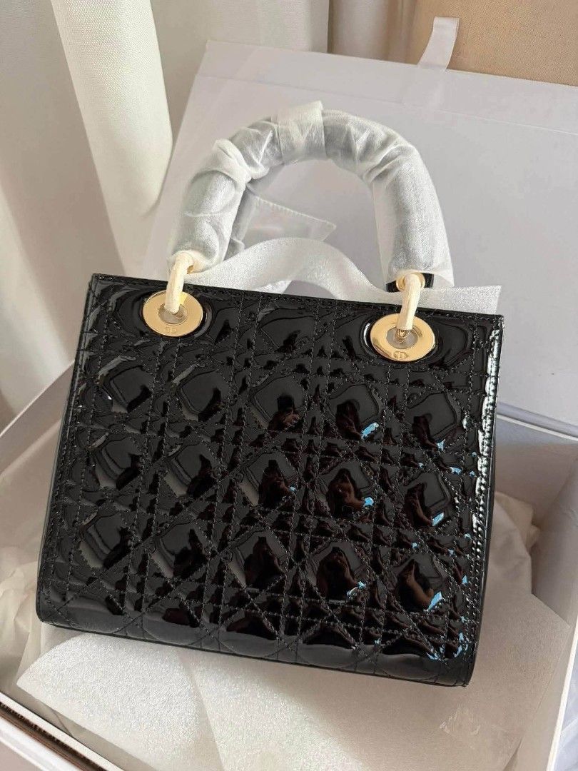 Christian Dior Lady Dior (Category: Luxury Bags & Wallets) located in Santa Cruz. Submitted by Authentic_Branded_Bags (Listing ID 1454514508, Image 2). Description: Christian Dior Lady Dior satchel in black patent leather with the iconic cannage stitching and gold-finish charms. The bag features a quilted texture created by the signature cannage motif. It is adorned with pale gold-finish "D.I.O.R." charms. This style can be carried by hand or wor
