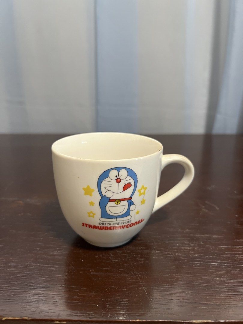 Doraemon cup (Category: Coffee & Tea Tableware) located in Manila. Submitted by rlab_japan_thrift (Listing ID 1454461092, Image 1). Description: Vintage Doraemon Strawberry Cones Ceramic cup🔔✨ Adorable vintage Japanese Doraemon ceramic cup featured with official Fujiko-Pro branding and Strawberry Cones graphics. Great for collectors and anime fans! * Character: Doraemon * Brand/Collaboration: Fujiko-Pro / Strawberry Cones * Material: Ceramic / P