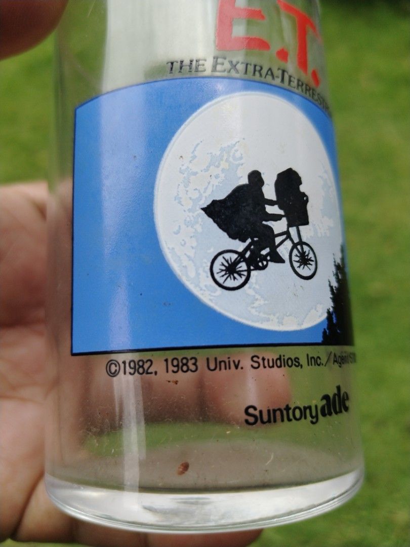 E.T. The Extra-Terrestrial Suntory Ade Glass (Category: Dinnerware & Cutlery) located in Legazpi City. Submitted by genobecollectives (Listing ID 1454384204, Image 2). Description: - Vintage Suntory Ade E.T. glass - Features iconic E.T. and Elliott biking scene with the moon - Copyright dates: 1982, 1983 - Ideal for collectors and fans of the movie E.T. - Great piece of movie memorabilia.