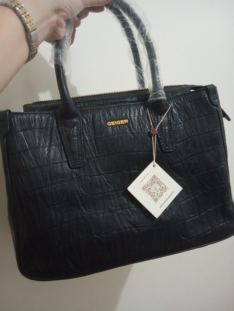 Geiger Black Croc Embossed Leather Handbag (Category: Luxury Bags & Wallets) located in Makati City. Submitted by bags_and_otherstuff (Listing ID 1454531859, Image 1). Description: - Brand new black leather handbag - Chic croc embossed texture - Elegant gold Geiger logo on the front - Top handles still have protective plastic on - Comes with original tag featuring QR code and website - Structured tote style for a polished look.