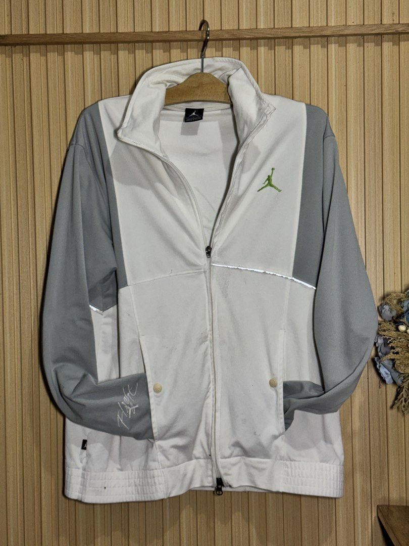Jordan Flight Track Jacket White Grey Green (Category: Coats, Jackets and Outerwear) located in Lagawe. Submitted by mochimades123 (Listing ID 1454491784, Image 1). Description: - Jordan track jacket - Color: White and Grey - Features green Jumpman logo on chest - Embroidered 'Flight' script on sleeve - Full zip closure - Includes pockets - Size: S - Made in Malaysia.