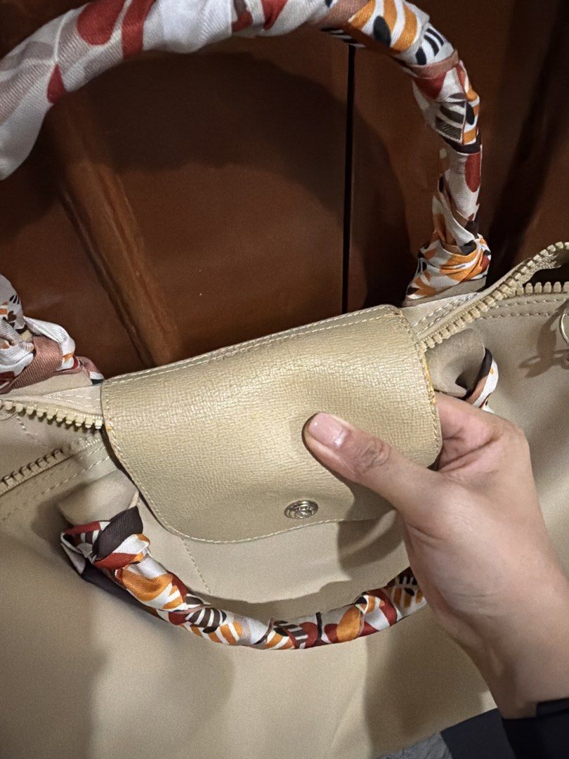 Authentic Longchamp Le Pliage Cuir Top Handle Bag with Scarf (Category: Luxury Bags & Wallets) located in Binangonan. Submitted by thingsbymargs (Listing ID 1454509113, Image 2). Description: - Beige Longchamp bag - Comes with a colorful scarf tied around the handles - Shows some wear on leather trim and strap attachments - Zipper closure - Great everyday bag with plenty of interior space -guaranteed original.