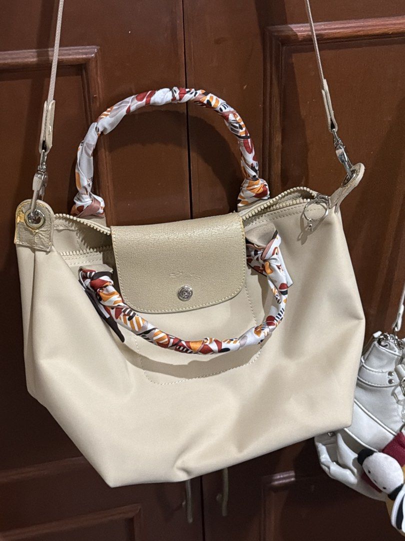 Authentic Longchamp Le Pliage Cuir Top Handle Bag with Scarf (Category: Luxury Bags & Wallets) located in Binangonan. Submitted by thingsbymargs (Listing ID 1454509113, Image 1). Description: - Beige Longchamp bag - Comes with a colorful scarf tied around the handles - Shows some wear on leather trim and strap attachments - Zipper closure - Great everyday bag with plenty of interior space -guaranteed original.