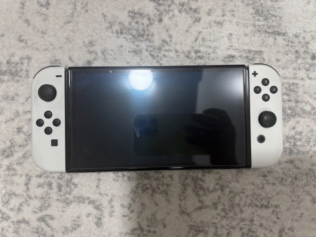 Nitendo Switch OLED (Category: Nintendo) located in Singapore. Submitted by alyshanazrie (Listing ID 1454528613, Image 2). Description: Selling my Nitendo Switch OLED cos i barely play it. Everything is in good working condition except that theres a little bit of paint splatter on the charging dock as you can see in the pic doesn’t affect anything tho just call it abstract BAHA. -full set with cables and joycons everything in the box - comes with
