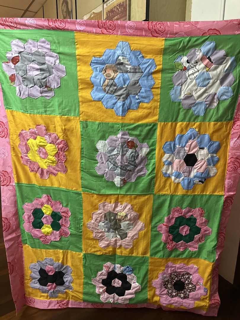Patchwork quilt (hand made) (Category: Bedding & Towels) located in Singapore. Submitted by yllwong (Listing ID 1454505142, Image 1). Description: - Handmade patchwork quilt - Features a vibrant floral border - Each square showcases a unique and intricate design - Some squares include charming character motifs - Adds a cozy and colorful touch to any room -measurement 2m x 1.5m.