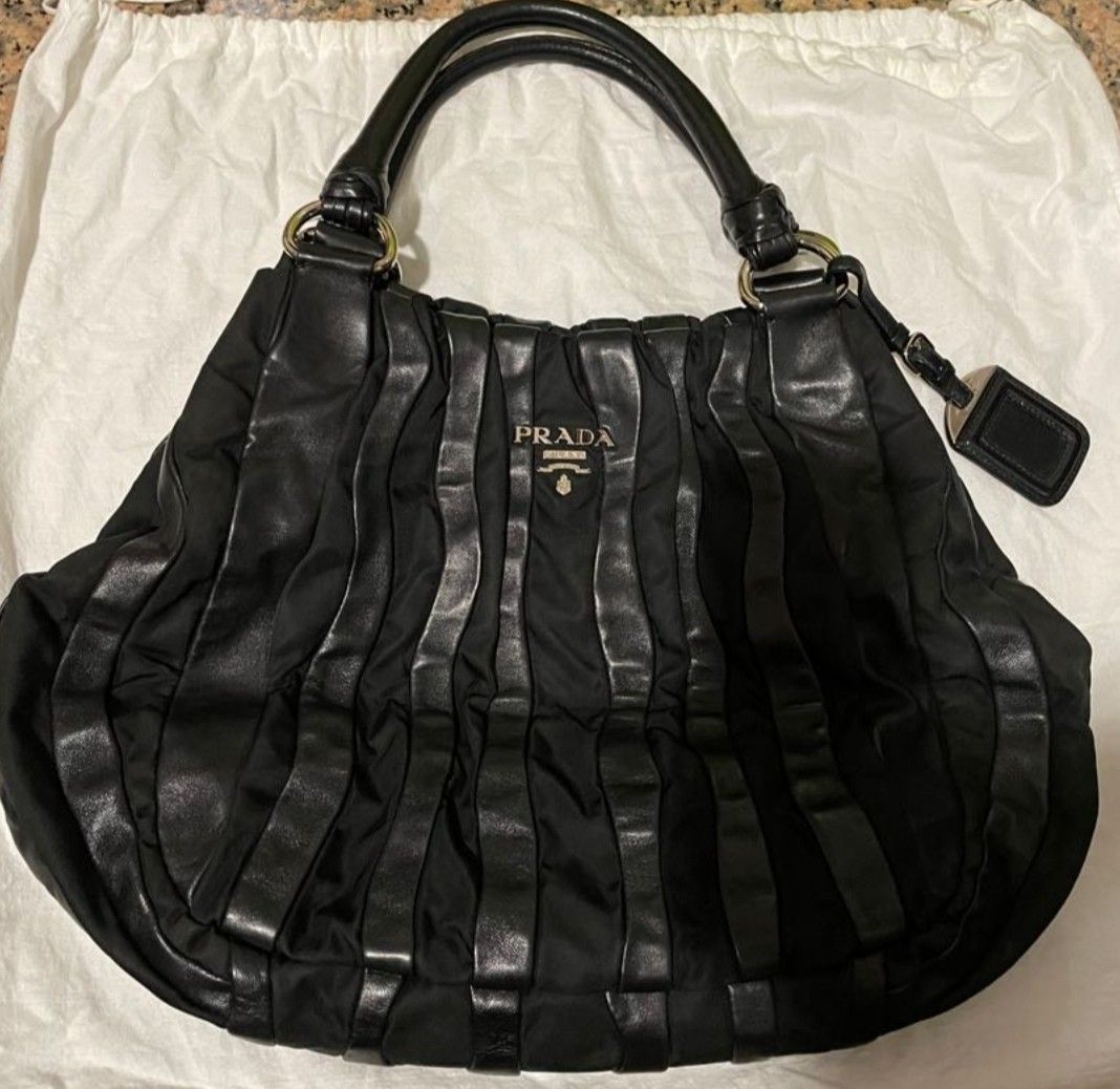 Prada Black Ruched Nylon Leather Shoulder Bag (Category: Luxury Bags & Wallets) located in Quezon City. Submitted by wisephoenix_00ffcd (Listing ID 1454397535, Image 1). Description: - Authentic Prada bag - Color: Black - Material: Nylon with leather trim - Design: Ruched detailing, gathered style - Features: Leather handles, Prada logo on front - Includes: Prada dust bag - Style: Chic, perfect for everyday use.